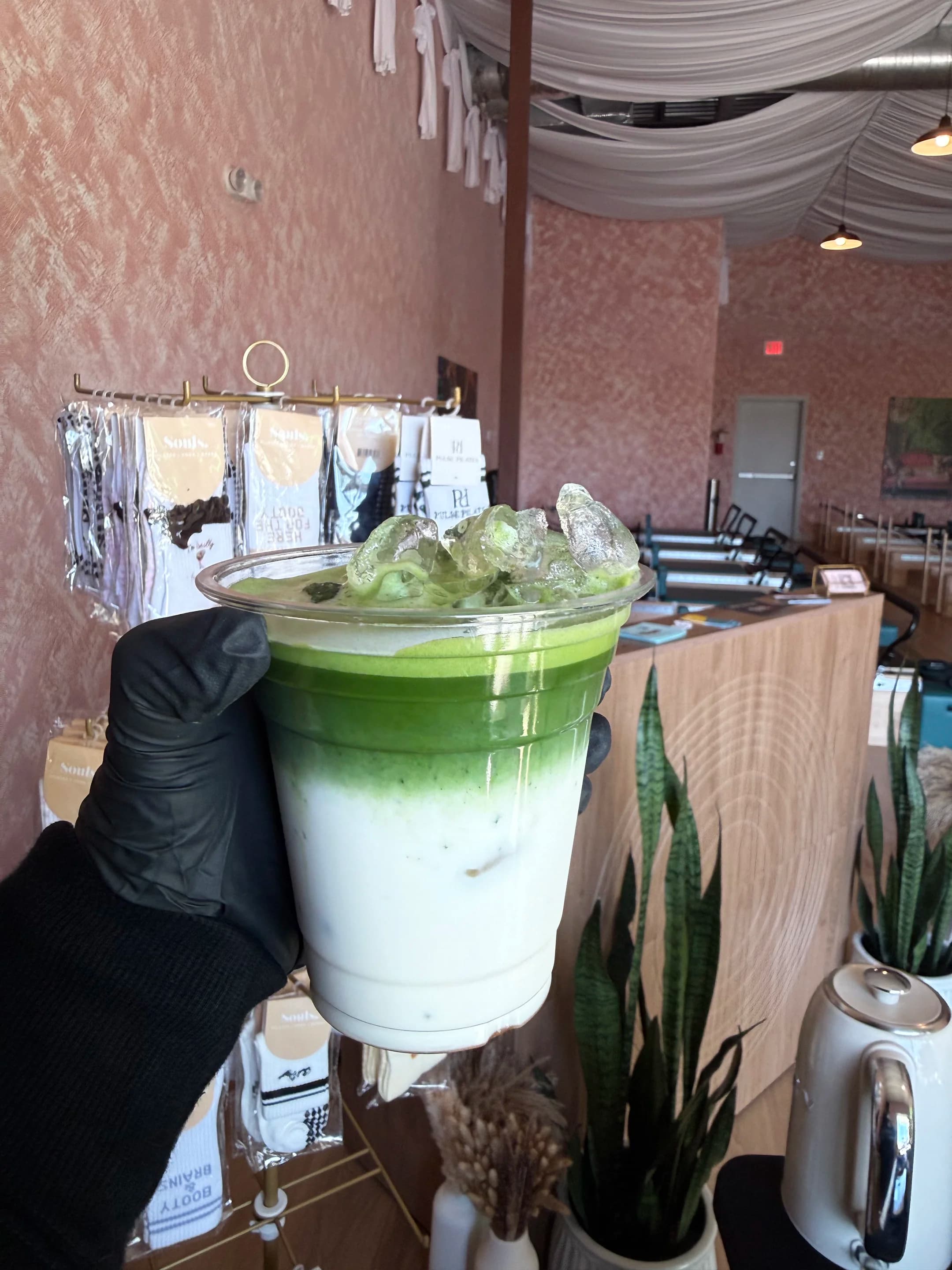 a gloved hand holding a finished matcha latte at a pop-up